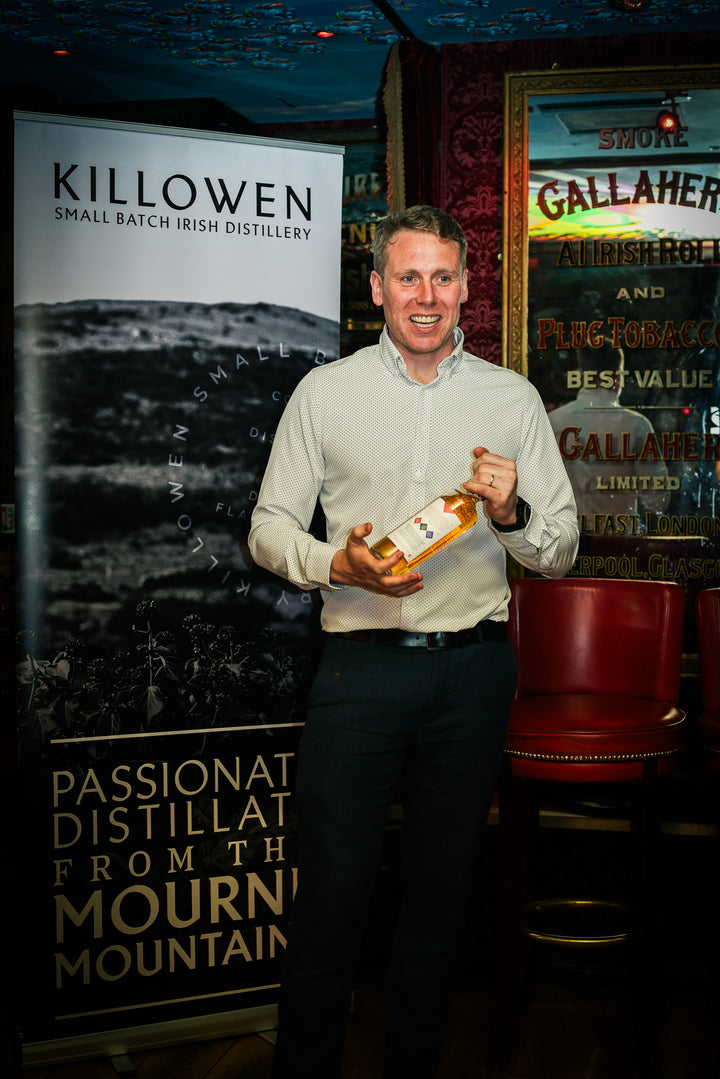Killowen whiskey bottle shared with guests beside the Killowen Distillery banner