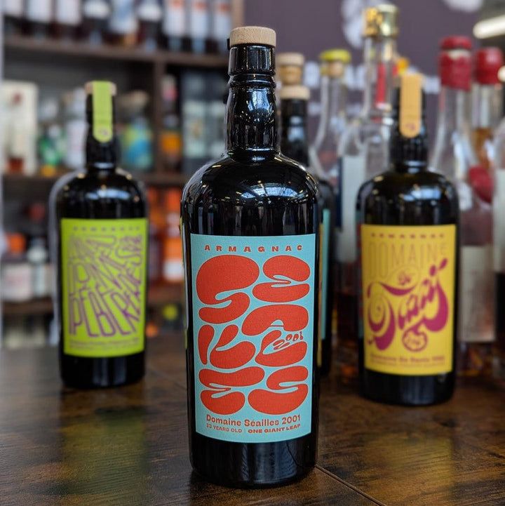 Three bottles of Armagnac on a wooden surface with a blurred bar background