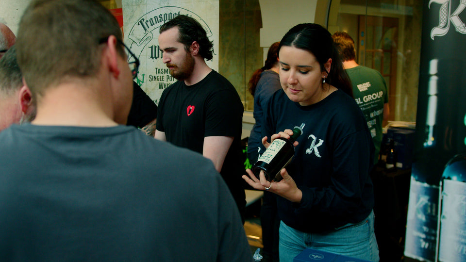 Kilara whiskey brand rep showing a bottle of Tasmanian single pot still whisky to attendees at Belfast Whiskey Week