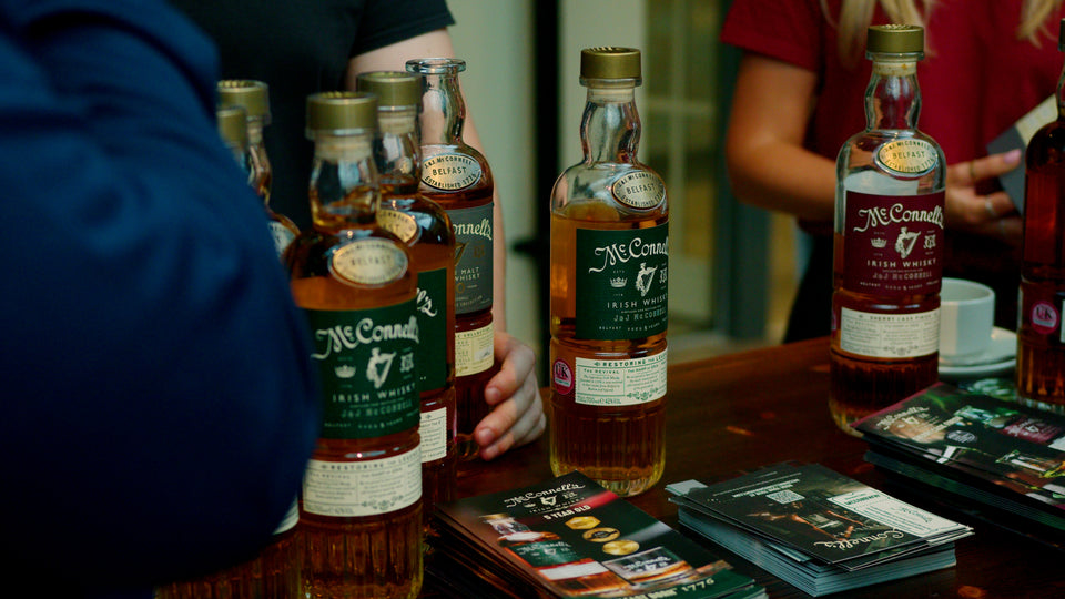 McConnell's Irish Whisky bottles displayed on a tasting table at Belfast Whiskey Week, with brand brochures