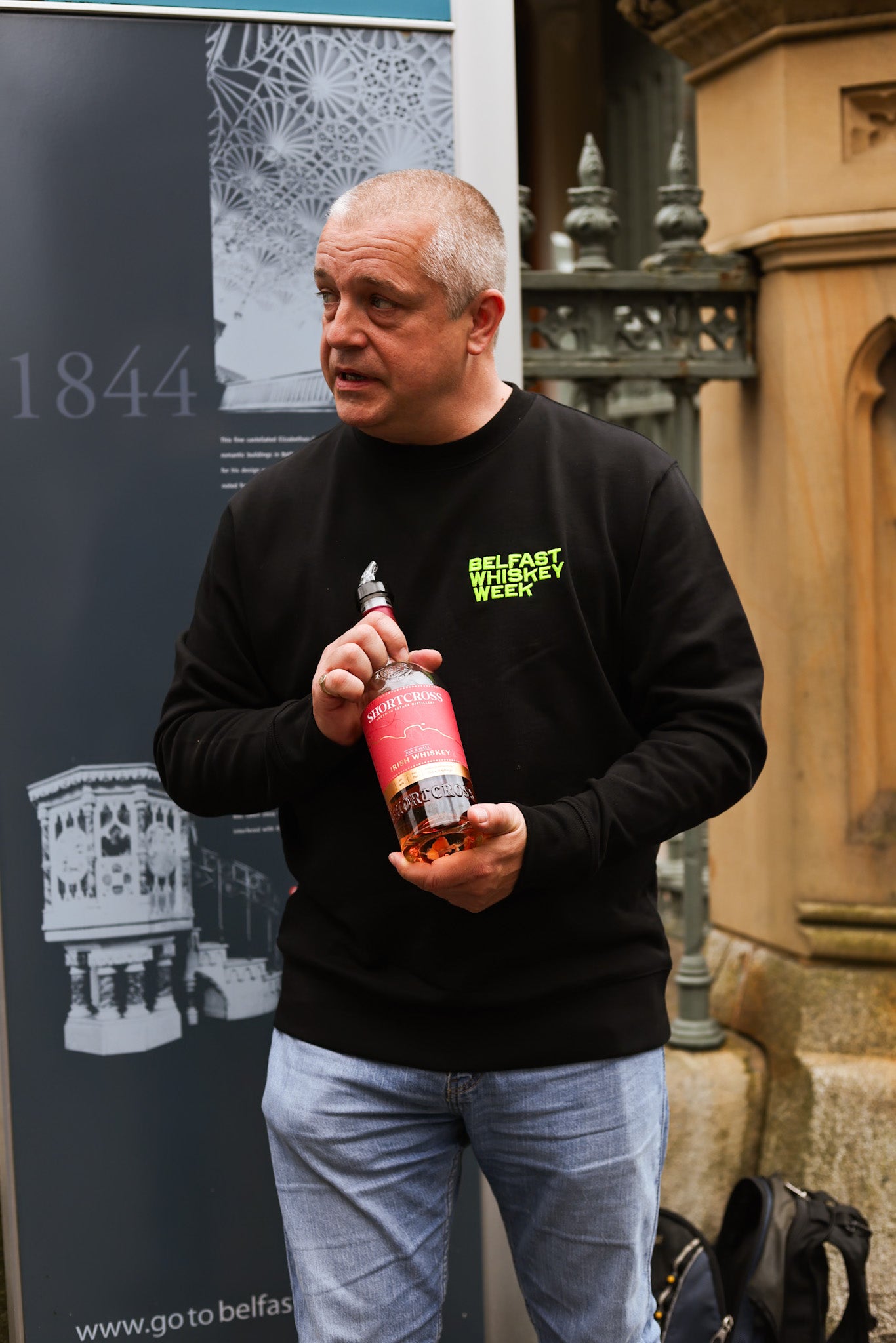 Marty speaking with a whiskey bottle in hand