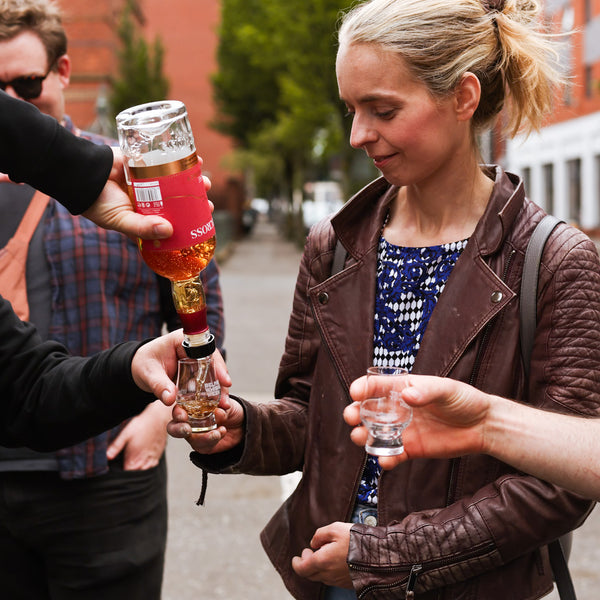 Pouring a dram for a guest in blue top and brown leather jacket