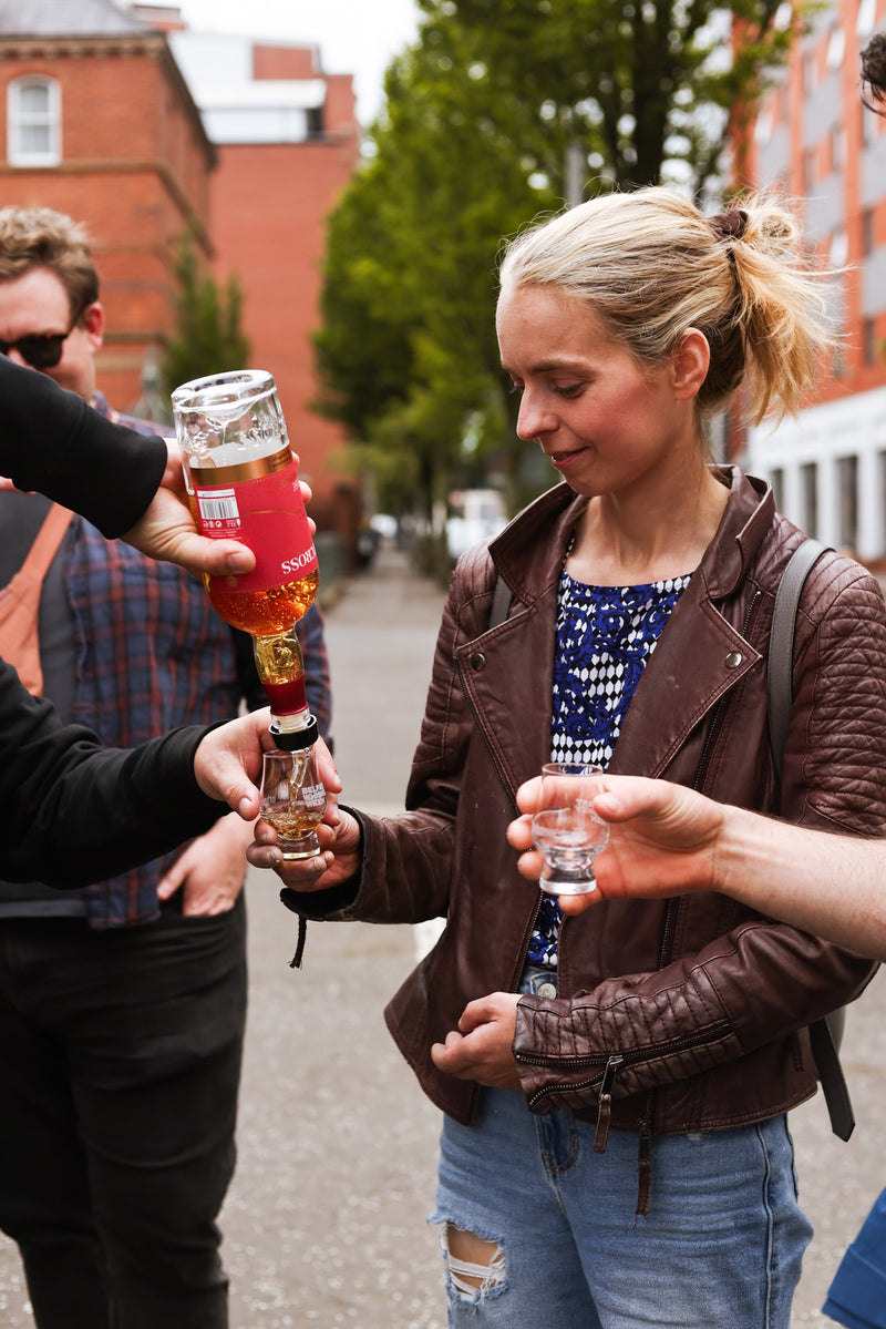 Pouring a dram for a guest in blue top and brown leather jacket