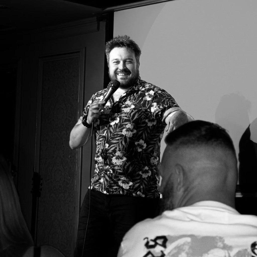 Comedy host on stage with microphone during a Belfast Whiskey Week fringe event
