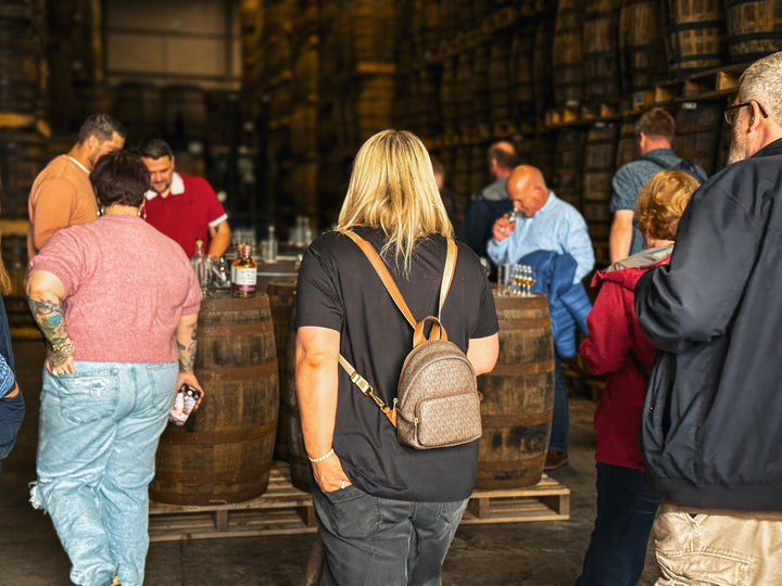 Tour group tasting whiskey among the casks in the Hinch Distillery warehouse