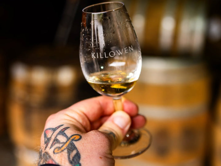 Killowen tasting glass of cask-strength whiskey held up in the barrel room