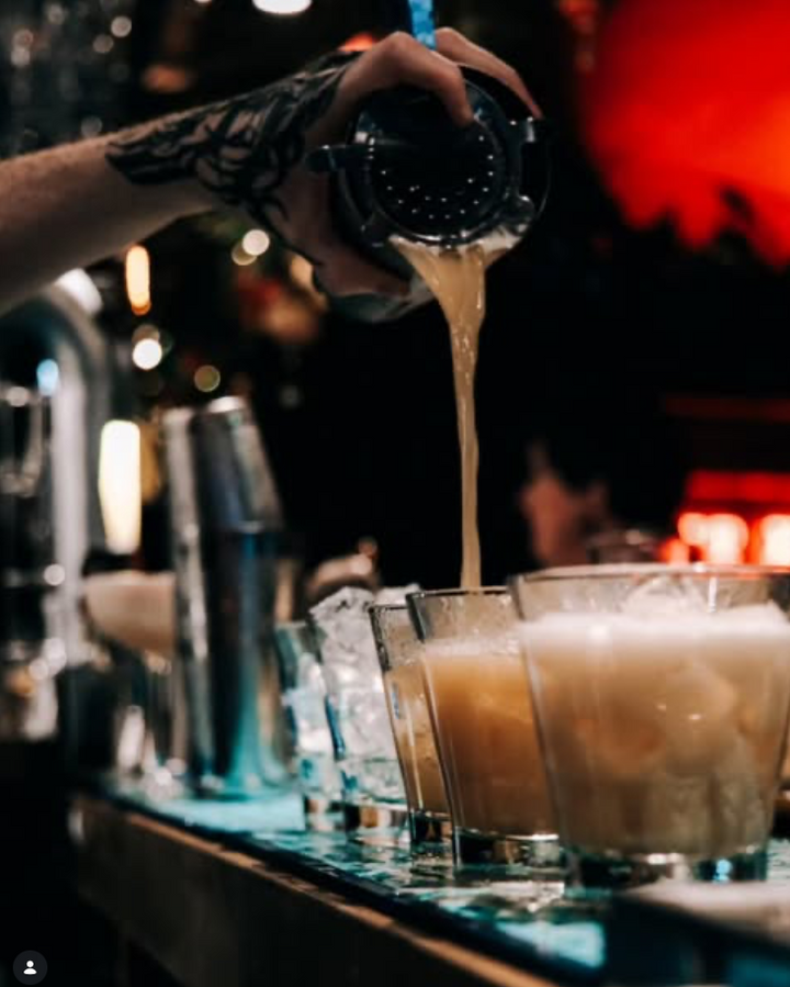 Bartender straining a cocktail into ice-filled glasses — Classic Cocktails After Dark at Muriel's Cafe Bar, Belfast Whiskey Week 2026